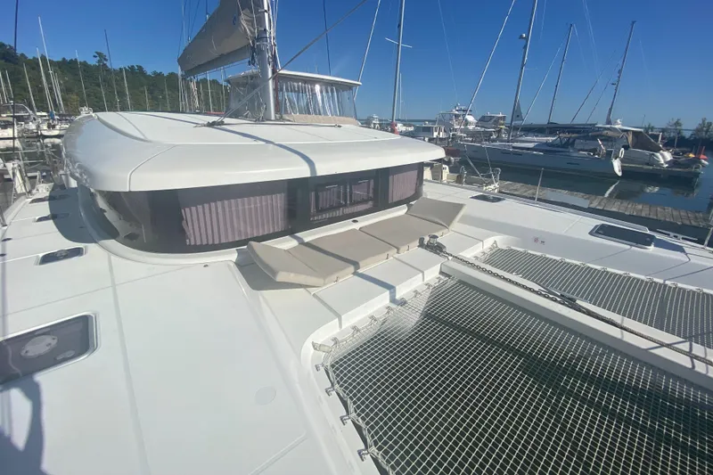 Slide: The Image of 2022 Lagoon 42 catamaran docked at marina, featuring spacious deck and netting. - 4