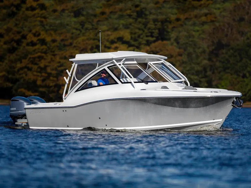 The Image of 2025 Albemarle 31DC boat cruising on a lake with forested background. - 0