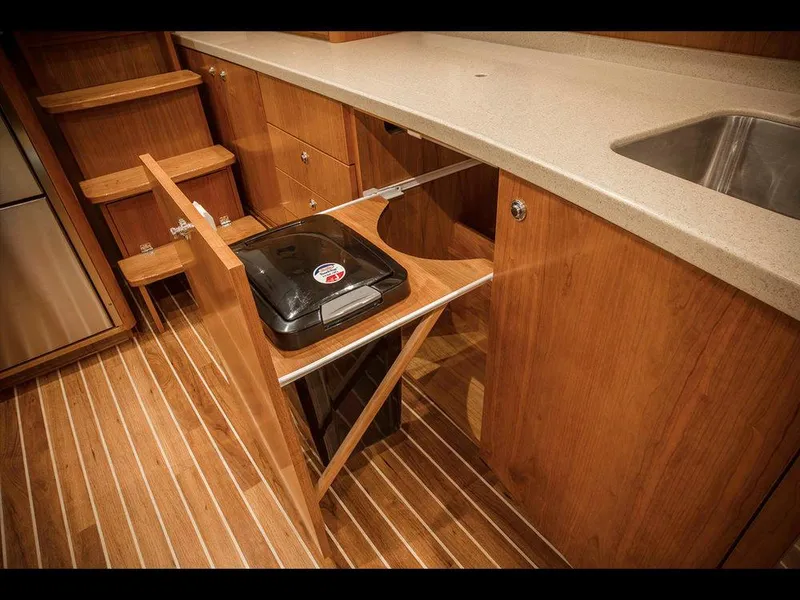 Slide: The Image of 2025 Albemarle 410 Express Fisherman kitchen with pull-out trash bin and wooden cabinetry. - 16