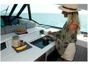 Slide: The Image of 2024 Formula 500 Super Sport Crossover yacht interior with woman cooking in the kitchen. - 34