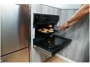 Slide: The Image of Person using a modern oven in a 2024 Formula 500 Super Sport Crossover kitchen. - 35