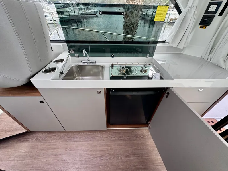 Slide: The Image of 2025 Beneteau Antares 11 kitchen area with sink, stove, and storage. - 17