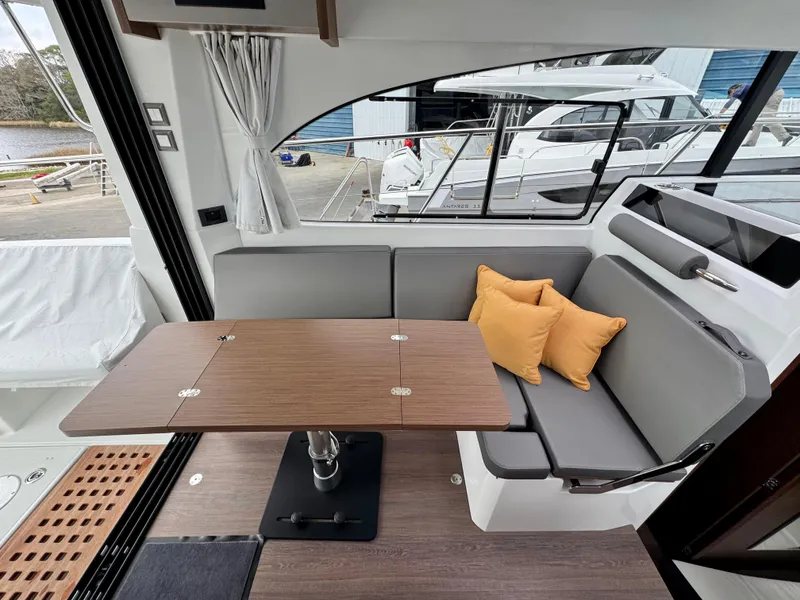 Slide: The Image of 2025 Beneteau Antares 11 interior with gray seating, wooden table, and yellow cushions. - 20