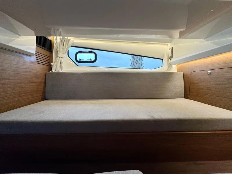 Slide: The Image of 2025 Beneteau Antares 11 cabin interior with window and cushioned seating. - 23