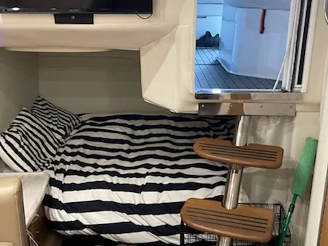 Slide: The Image of 2014 Rinker 360 Express Cruiser interior with striped bedding and wooden steps. - 14