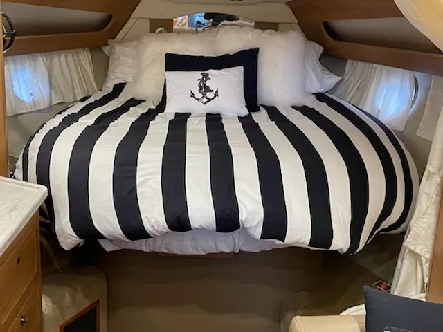 Slide: The Image of 2014 Rinker 360 Express Cruiser cabin with striped bedding and anchor pillow. - 15