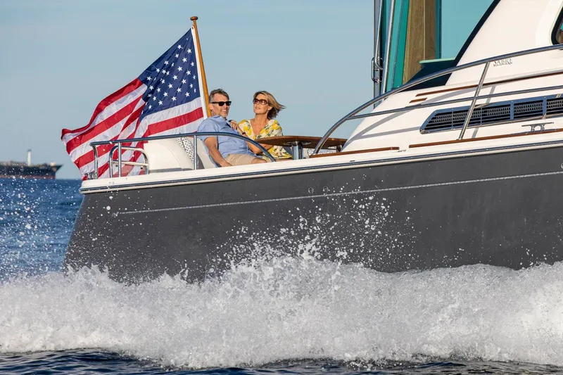 Slide: The Image of Couple enjoying a ride on a 2025 Sabre 58 Salon Express yacht with American flag. - 15