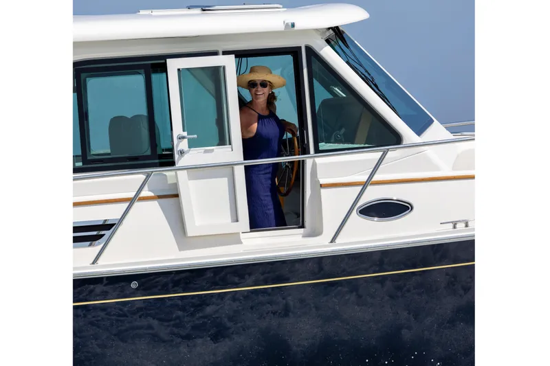 Slide: The Image of Woman steering 2027 Back Cove 412 yacht, wearing a sun hat and sunglasses. - 3