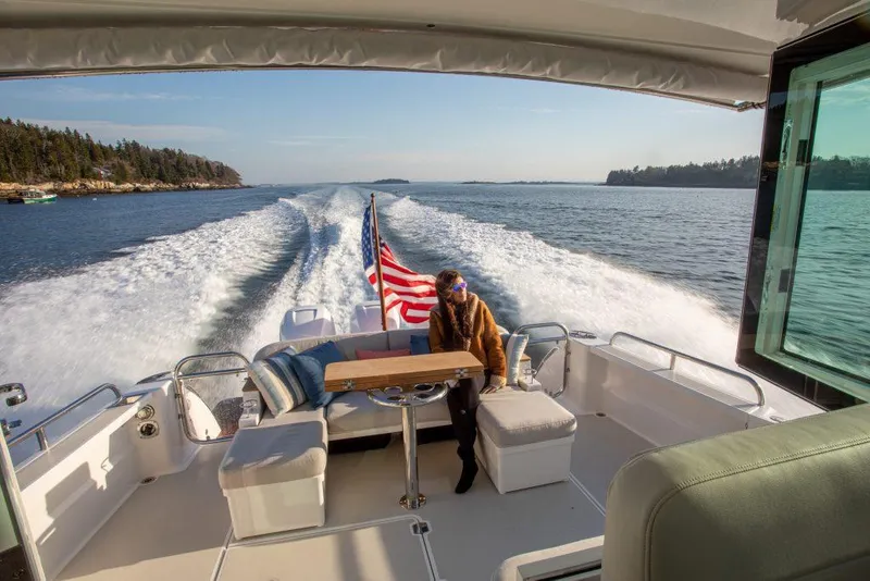 Slide: The Image of Back Cove 390 (2025) cruising on open water, rear deck view with American flag. - 3