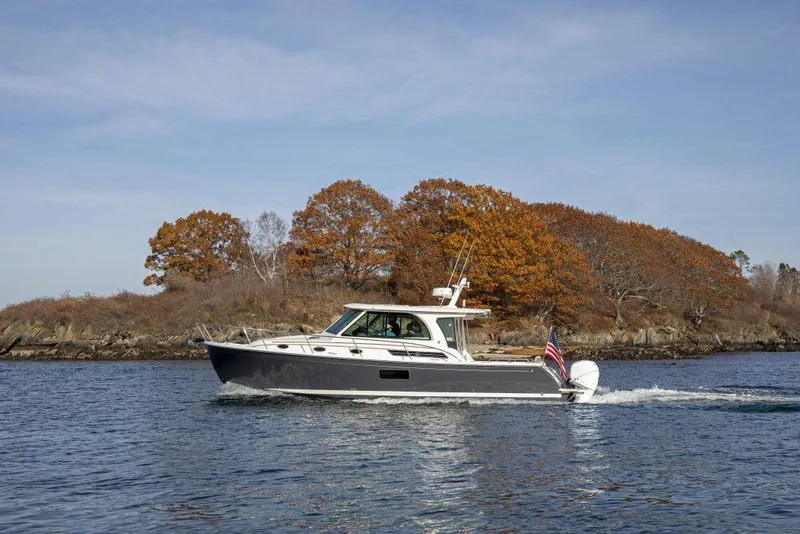 Slide: The Image of 2025 Back Cove 390 boat cruising on a lake with autumn trees in the background. - 34