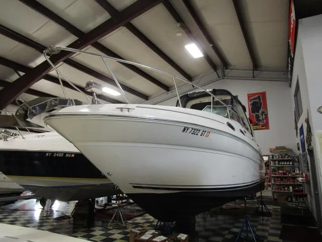 The Image of 2004 Sea Ray 260 Sundancer boat in indoor storage, showcasing sleek design and white exterior. - 1
