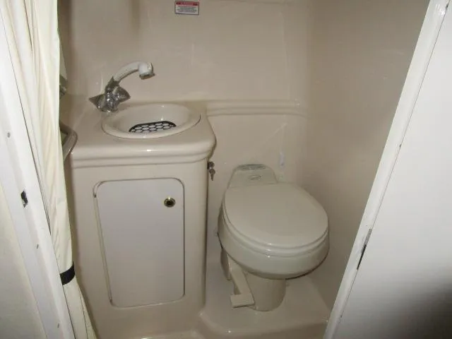 Slide: The Image of Compact bathroom in 2004 Sea Ray 260 Sundancer boat, featuring sink and toilet. - 15