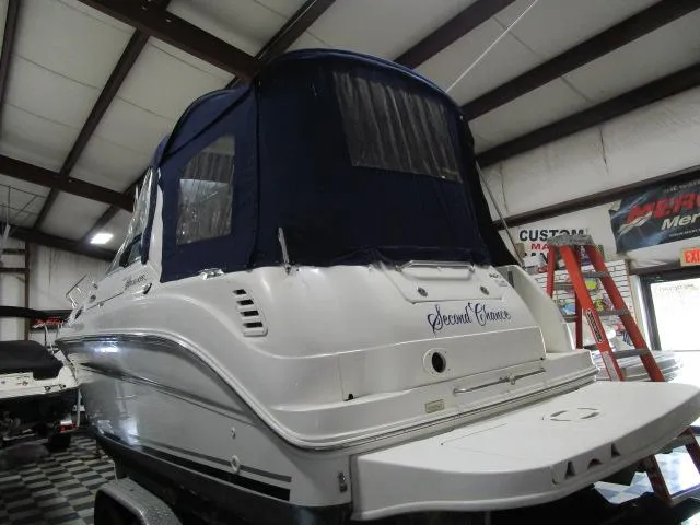 Slide: The Image of 2004 Sea Ray 260 Sundancer boat with blue canopy in indoor storage. - 3