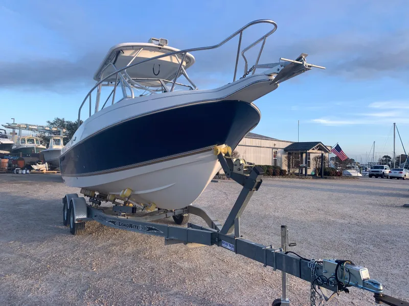 Slide: The Image of 2003 Aquasport 225 Explorer boat on a trailer in a marina. - 10
