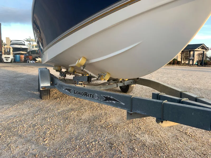 Slide: The Image of 2003 Aquasport 225 Explorer boat on Load Rite trailer in a gravel lot. - 11