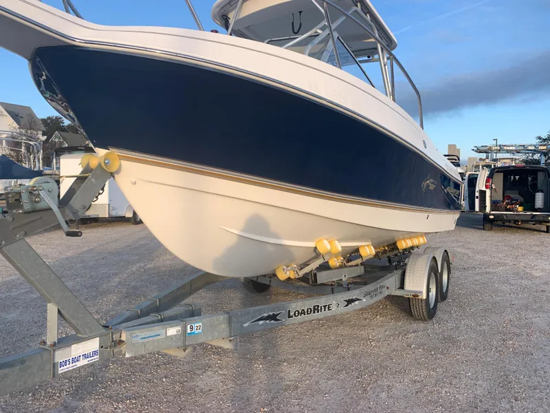 Slide: The Image of 2003 Aquasport 225 Explorer boat on Load Rite trailer in a parking lot. - 12