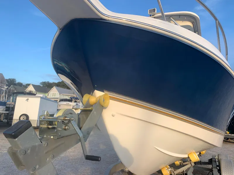 Slide: The Image of 2003 Aquasport 225 Explorer boat on a trailer, blue and white hull. - 13