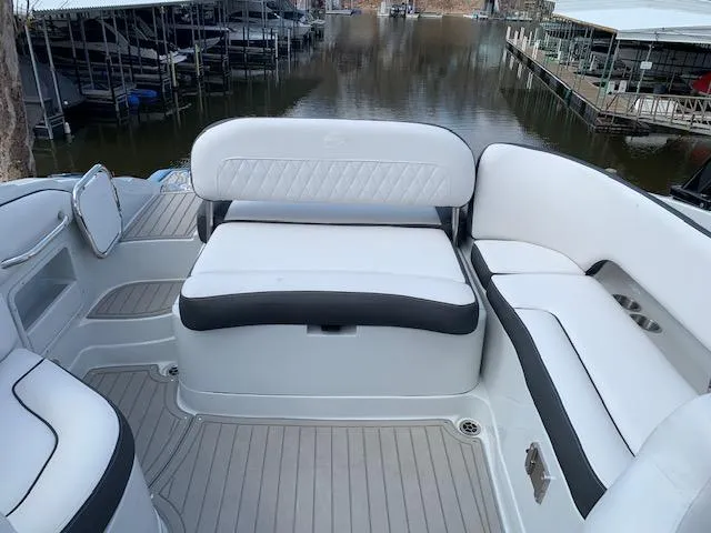 Slide: The Image of 2022 Crownline 255 SS boat interior with white and black seating, docked at marina. - 2