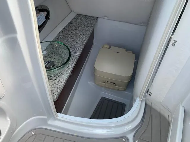 Slide: The Image of 2022 Crownline 255 SS boat interior bathroom with granite countertop and portable toilet. - 6
