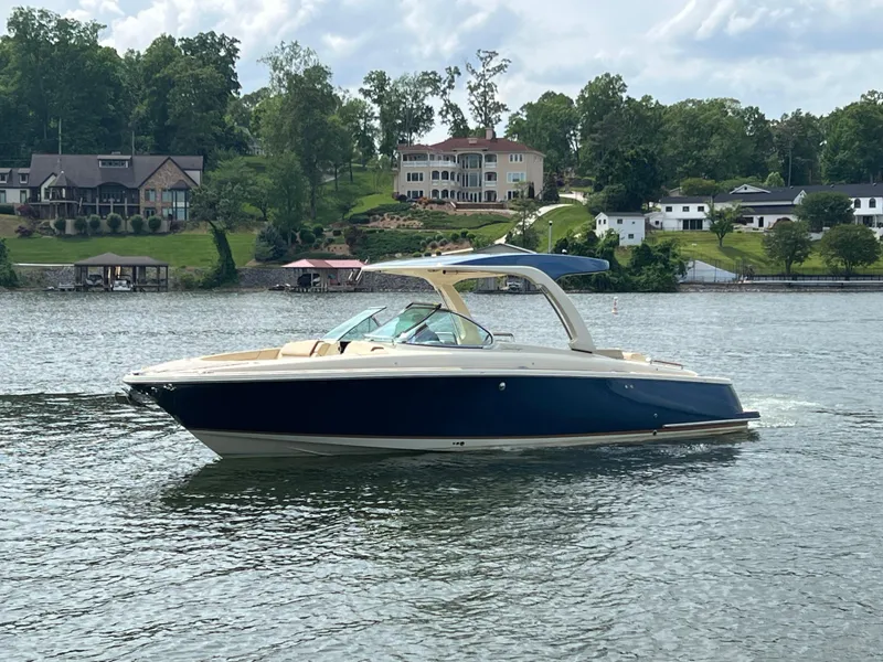 The Image of 2020 Chris-Craft Launch 31 GT boat cruising on a lake with houses in the background. - 0