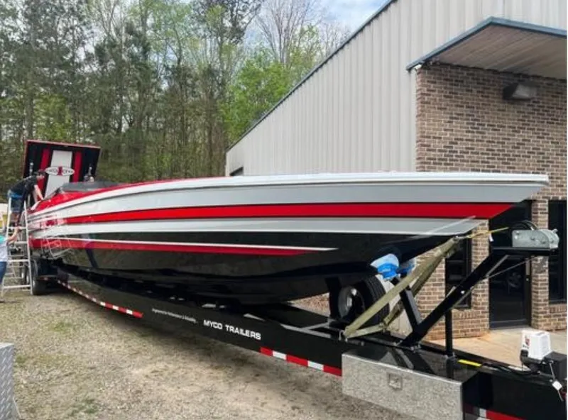 Slide: The Image of 2016 Cigarette 50' Marauder boat on trailer, red and black design, parked near a building. - 28