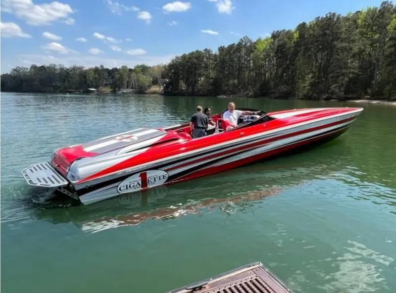 Slide: The Image of 2016 Cigarette 50' Marauder speedboat on a serene lake with lush forest backdrop. - 5