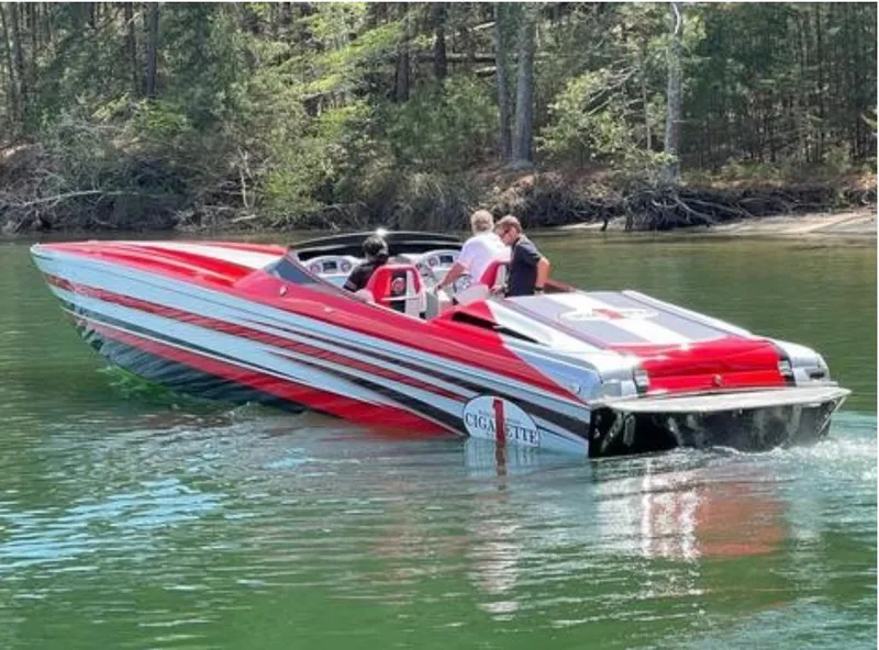Slide: The Image of 2016 Cigarette 50' Marauder speedboat with red and silver stripes on a calm lake. - 6
