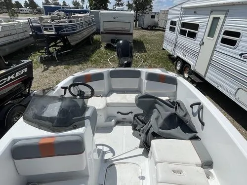 Slide: The Image of 2019 Tahoe T16 boat interior with seating and steering wheel, parked among RVs and trailers. - 11