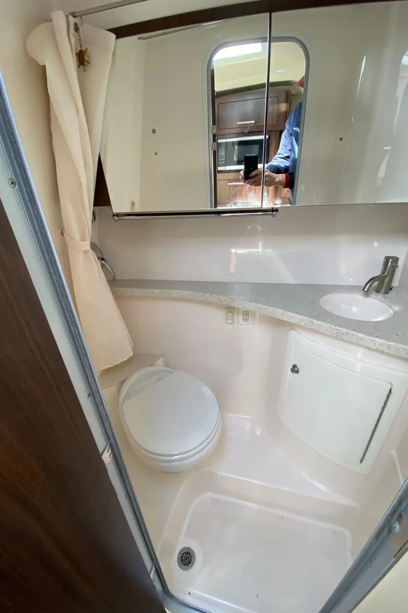 Slide: The Image of 2018 Regal 28 Express boat bathroom with toilet, sink, and mirror. - 11