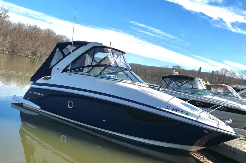 Slide: The Image of 2018 Regal 28 Express boat docked on a calm lake under a clear blue sky. - 3