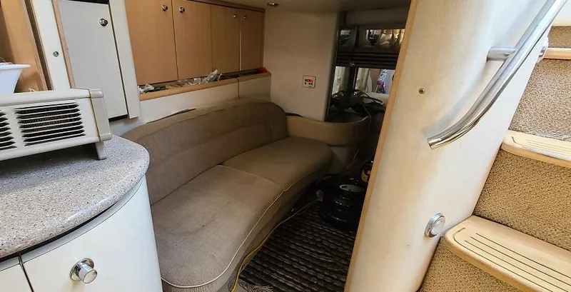 Slide: The Image of 1999 Bayliner 4085 Avanti interior with beige seating and compact kitchen area. - 20
