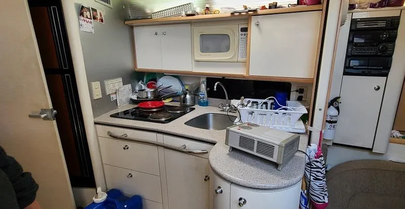 Slide: The Image of Compact kitchen area in a 1999 Bayliner 4085 Avanti boat with sink, stove, and microwave. - 23