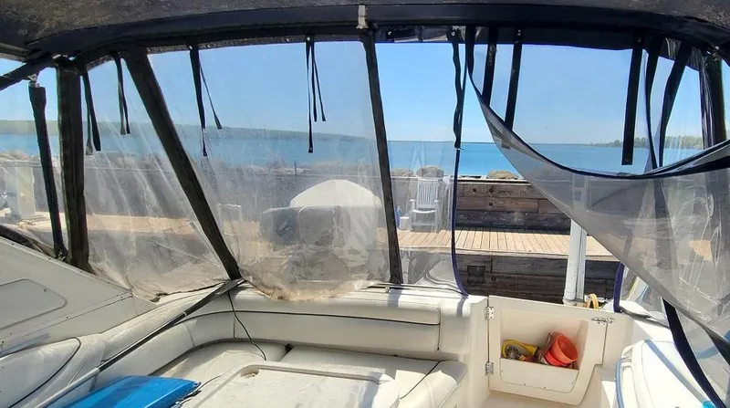 Slide: The Image of Interior view of 1999 Bayliner 4085 Avanti boat with clear canopy and waterfront background. - 8