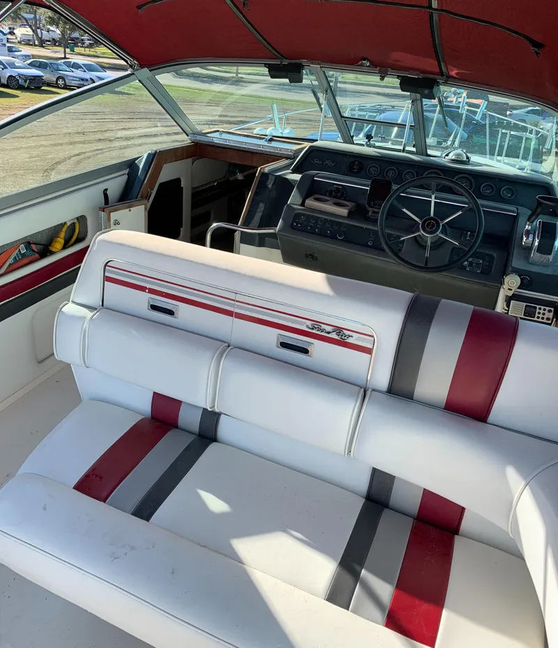 Slide: The Image of 1991 Sea Ray 290 Sundancer boat interior with red and gray seating and dashboard. - 10