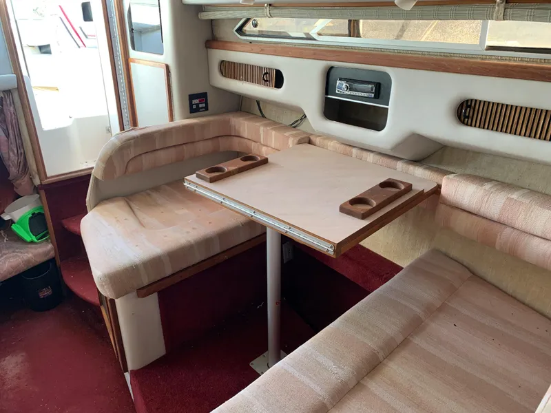 Slide: The Image of 1991 Sea Ray 290 Sundancer interior with beige seating and wooden table. - 2