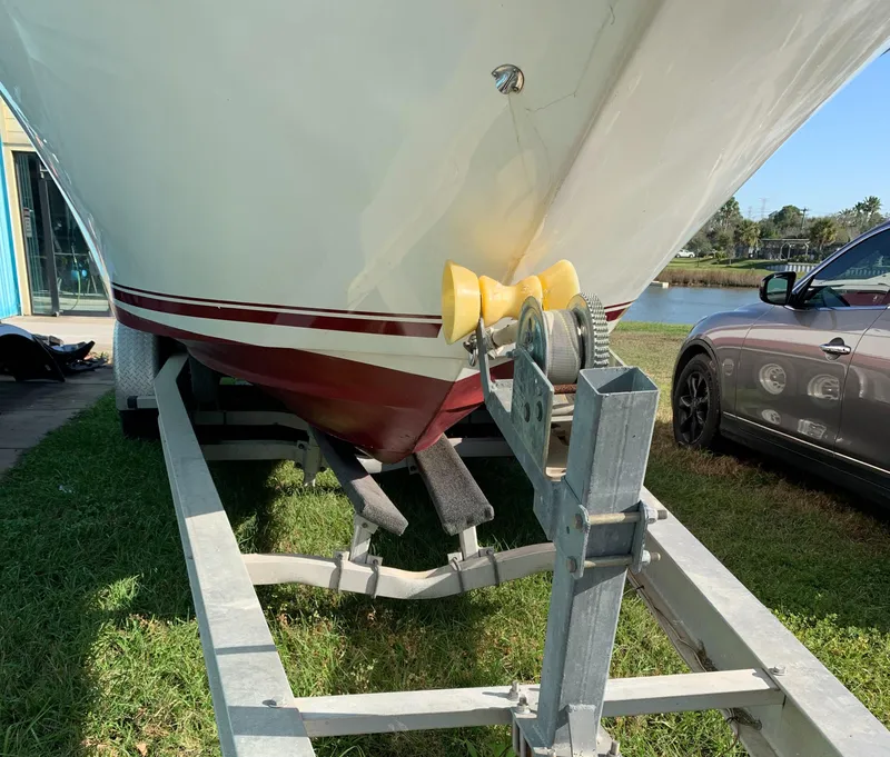 Slide: The Image of 1991 Sea Ray 290 Sundancer boat on trailer, parked on grass near a car. - 29