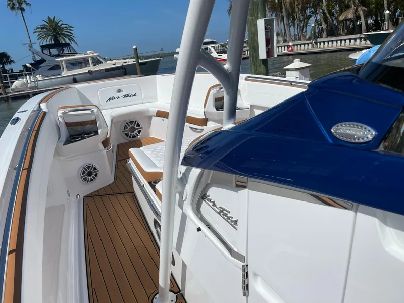 Slide: The Image of 2021 Nor-Tech 390 Sport boat interior with teak flooring and white seating at marina. - 30