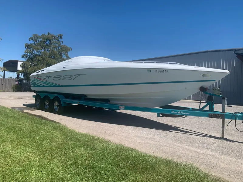 Slide: The Image of 1999 Baja 29 Outlaw SST boat on a trailer, parked outdoors. - 0