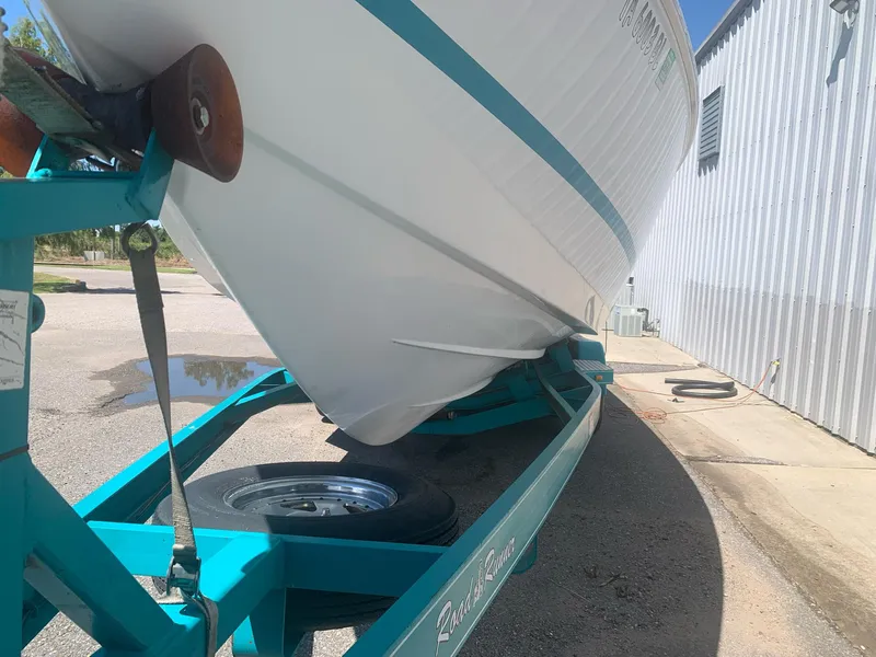 Slide: The Image of 1999 Baja 29 Outlaw SST boat on a teal trailer near a metal building. - 30