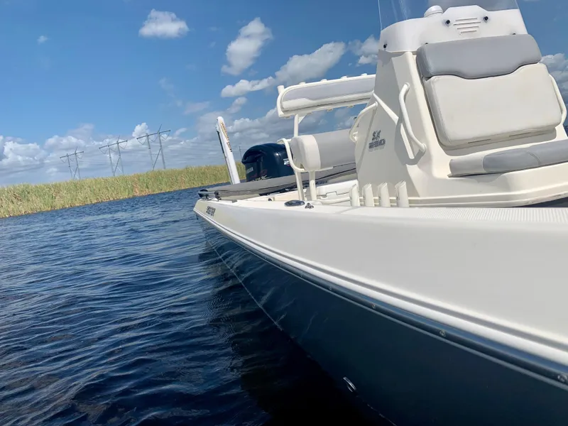 Slide: The Image of 2016 Skeeter SX230 boat on calm water under a blue sky with clouds. - 16