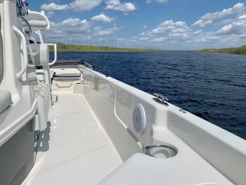 Slide: The Image of 2016 Skeeter SX230 boat on a calm lake under a blue sky with clouds. - 17