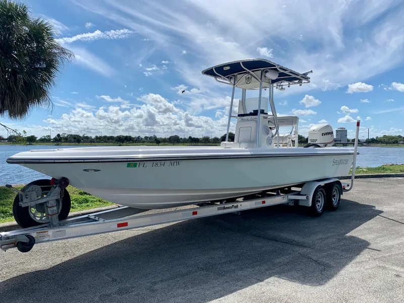 Slide: The Image of 2005 ShearWater z2400 boat on a trailer by a lake under a blue sky. - 0
