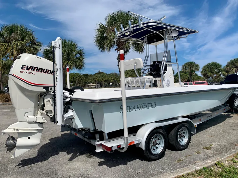 Slide: The Image of 2005 ShearWater z2400 boat on trailer with Evinrude engine, parked near palm trees. - 10