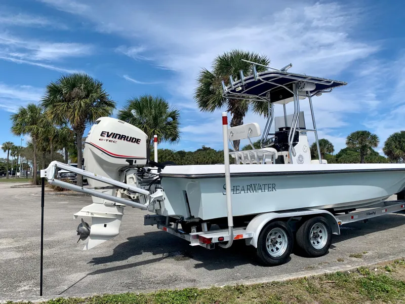 Slide: The Image of 2005 ShearWater z2400 boat on trailer with Evinrude engine, parked near palm trees. - 12