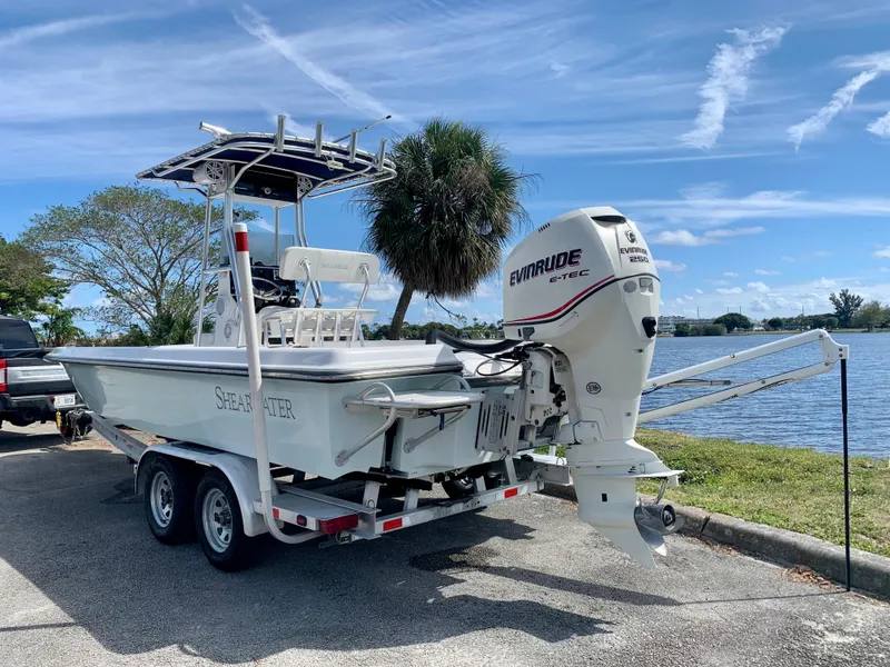 Slide: The Image of 2005 ShearWater z2400 boat on trailer with Evinrude outboard motor by a lake. - 13