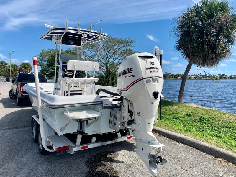 Slide: The Image of 2005 ShearWater z2400 boat with Evinrude 250 motor on trailer by a lake. - 3
