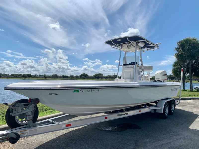 Slide: The Image of 2005 ShearWater z2400 boat on trailer by a lake. - 8