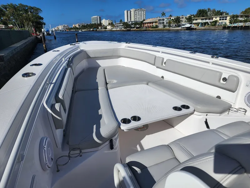 Slide: The Image of 2019 Everglades 365 boat with spacious seating and table on a sunny waterfront. - 15