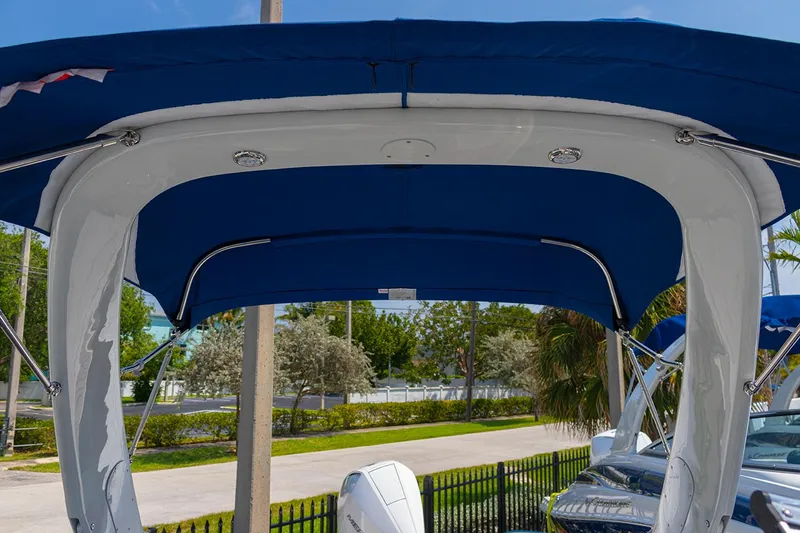 Slide: The Image of 2022 Crownline E 255 XS boat with blue canopy and outboard motor. - 21