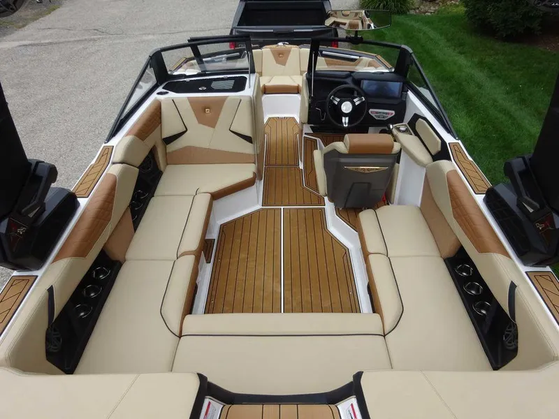 Slide: The Image of 2023 Nautique S21 boat interior with tan and white seating, teak flooring, and modern dashboard. - 7